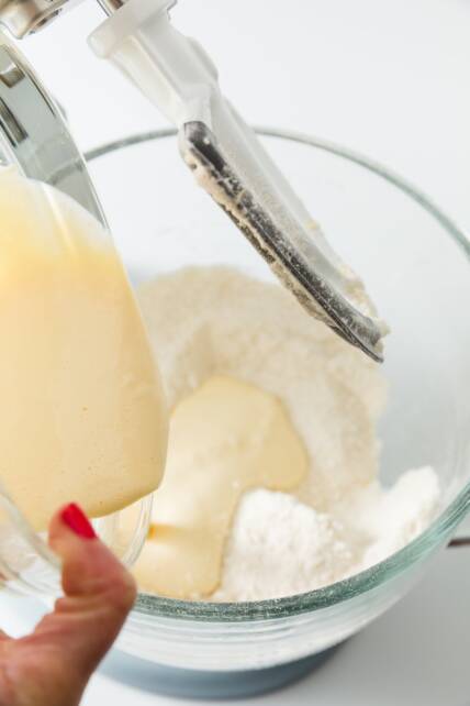 Mezcla de ingredientes húmedos en ingredientes secos en el tazón de una batidora de pie