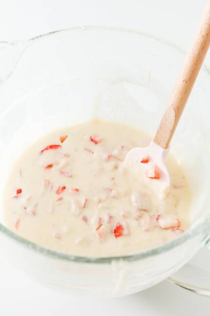 revolviendo las fresas en la masa con una espátula rosa