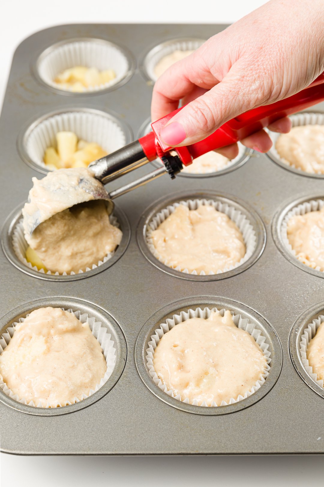 Adding batter to pineapple-upside down cupcakes