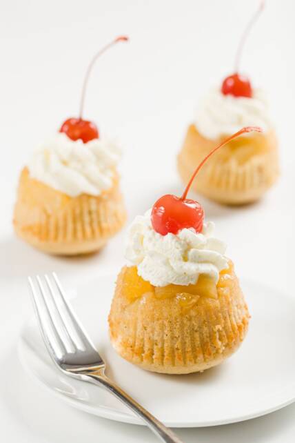 pastelitos de piña al revés cubiertos con crema batida y cerezas al marrasquino