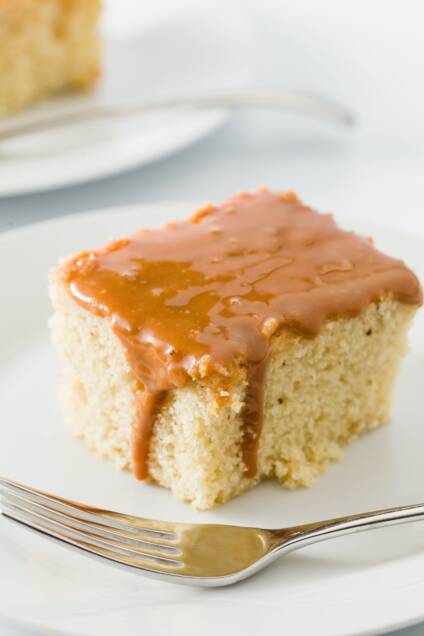 Slice of Dulce de leche cake on a plate with dulce de leche dripping down the side