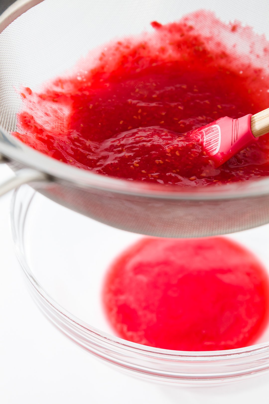 Straining raspberry seeds with sieve