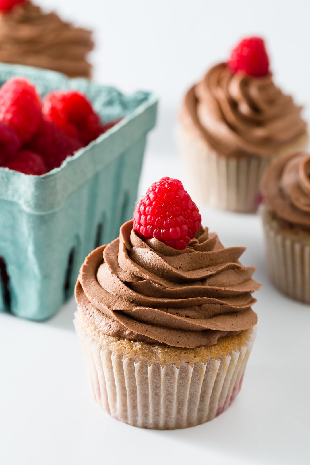 Raspberry cupcakes with raspberries in the background