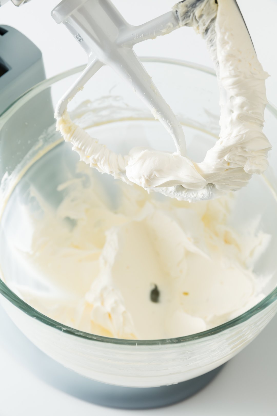 a view into an electric stand mixer bowl where cream cheese has been whipped with butter