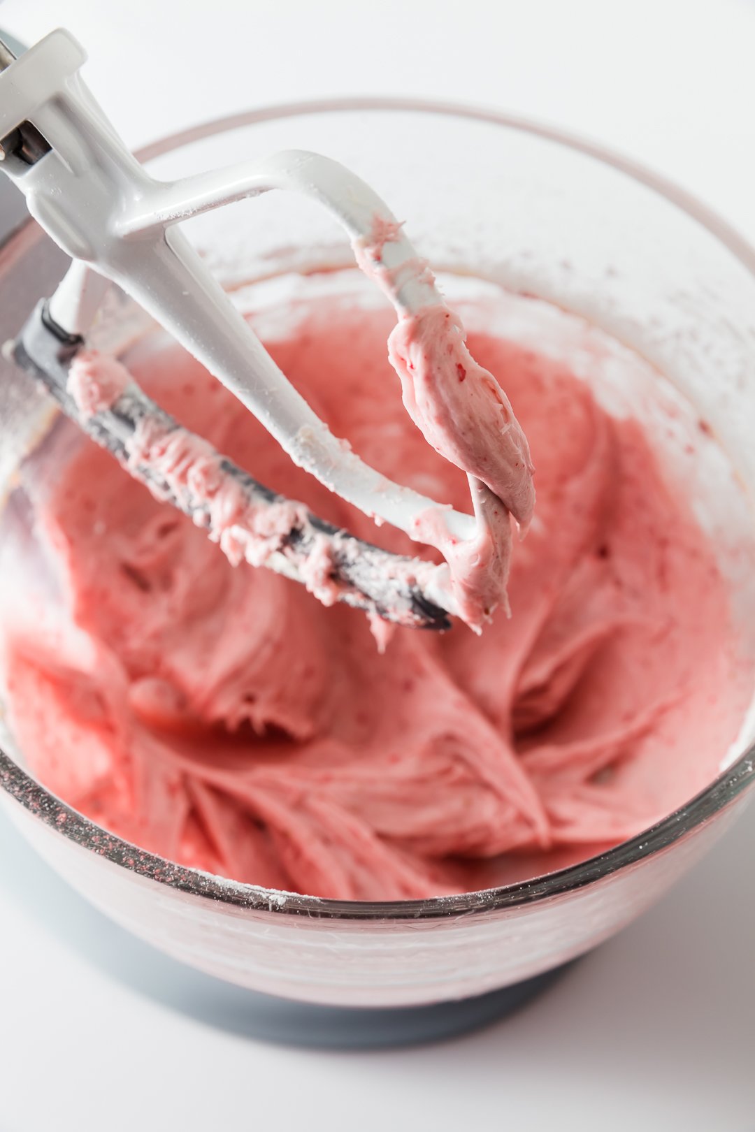 a view into an electric stand mixer bowl filled with strawberry cream cheese frosting without powdered sugar added