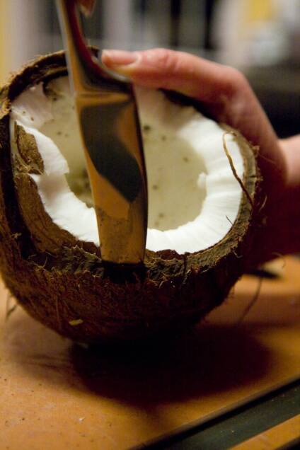 Cutting open a coconut to make desiccated coconut