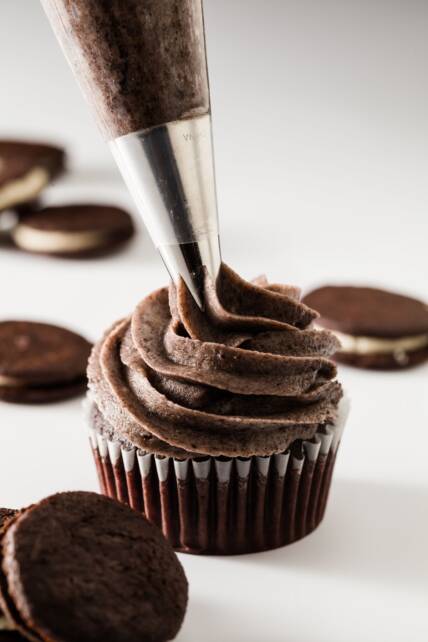 Galletas Oreo y glaseado de crema se canalizan sobre una magdalena