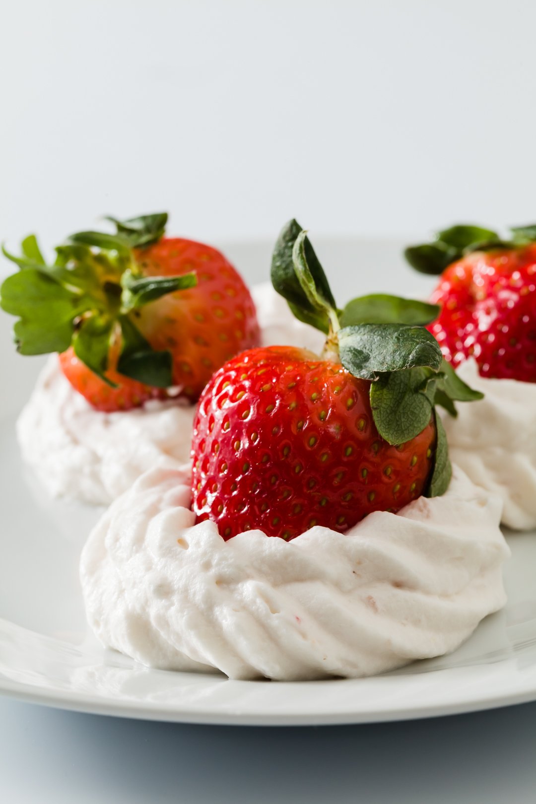 fresh strawberries sitting on top of fresh whipped cream