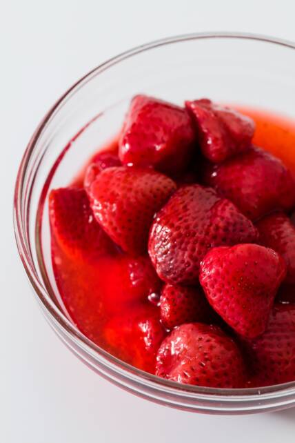 fresas congeladas descongeladas en un recipiente de vidrio con mucho jugo de fresa