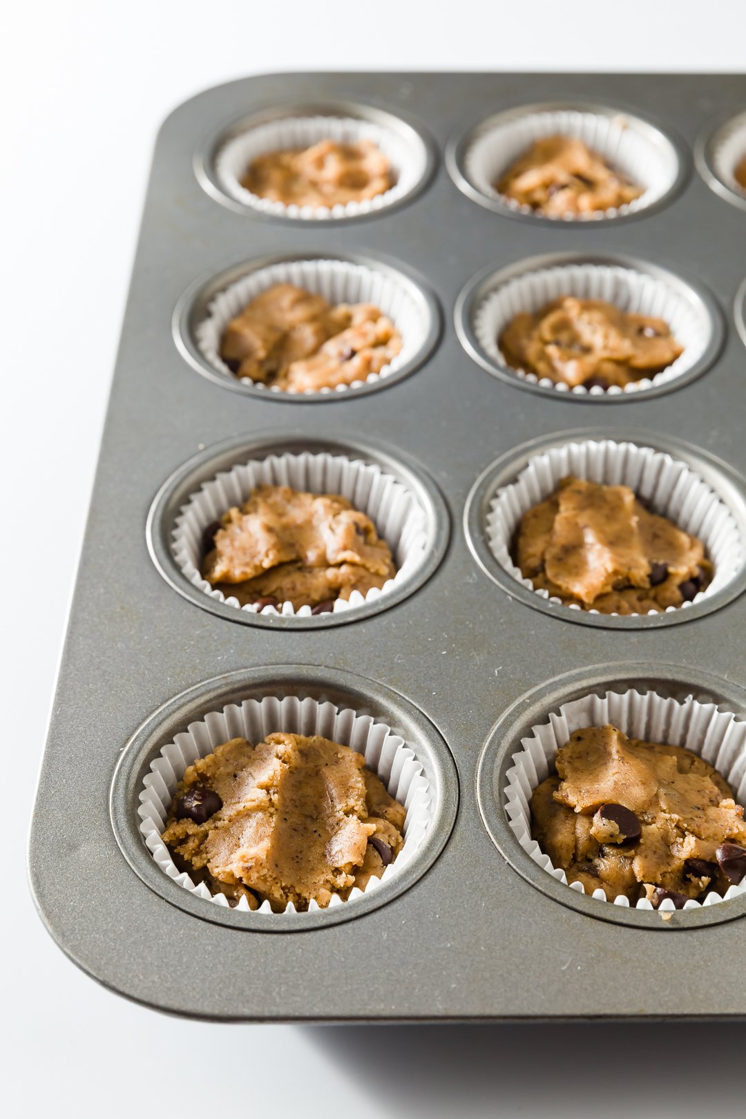 cupcake tin filled with cookie dough in cupcake liners