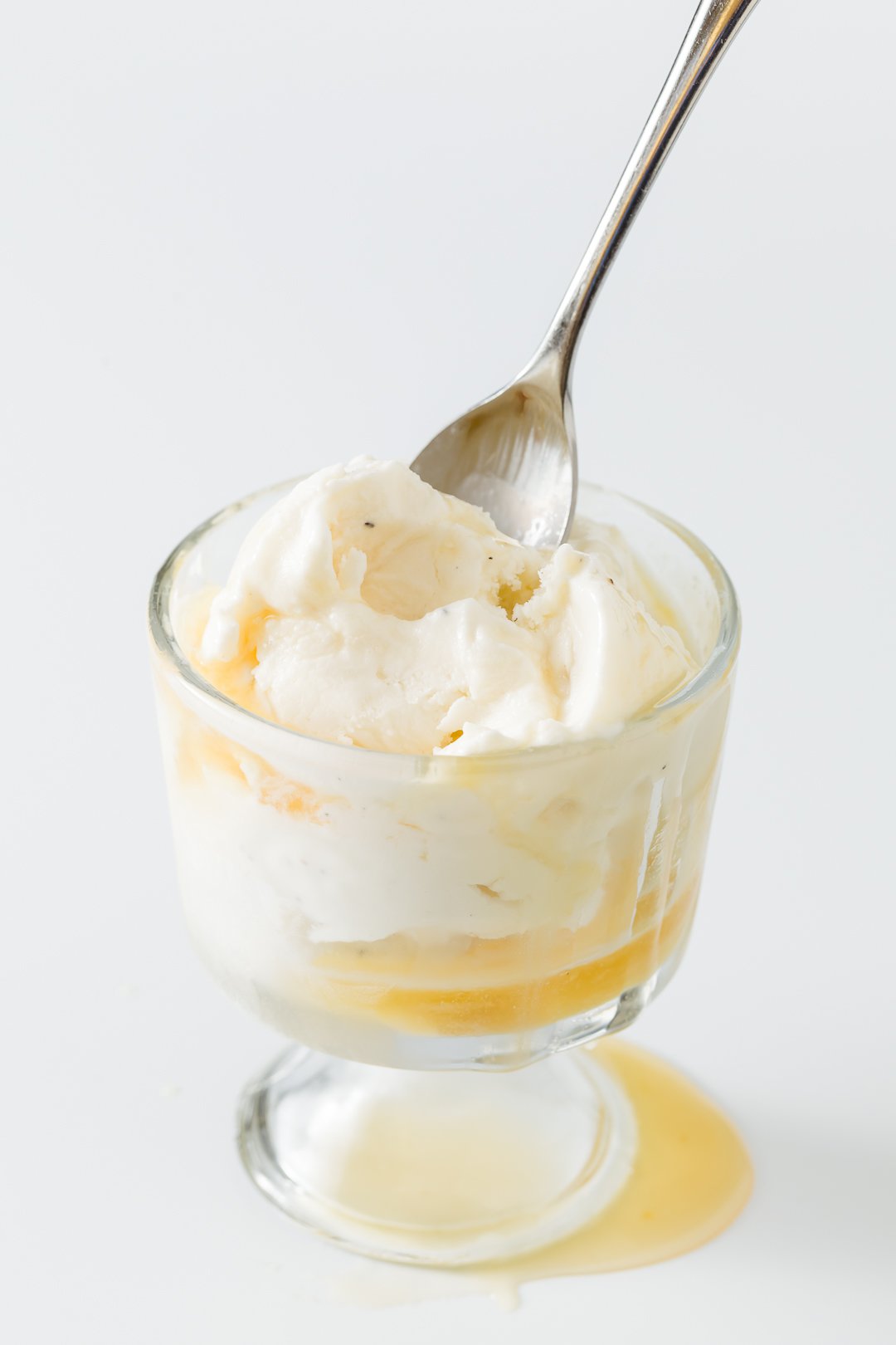 Orange sauce over ice cream with a spoon