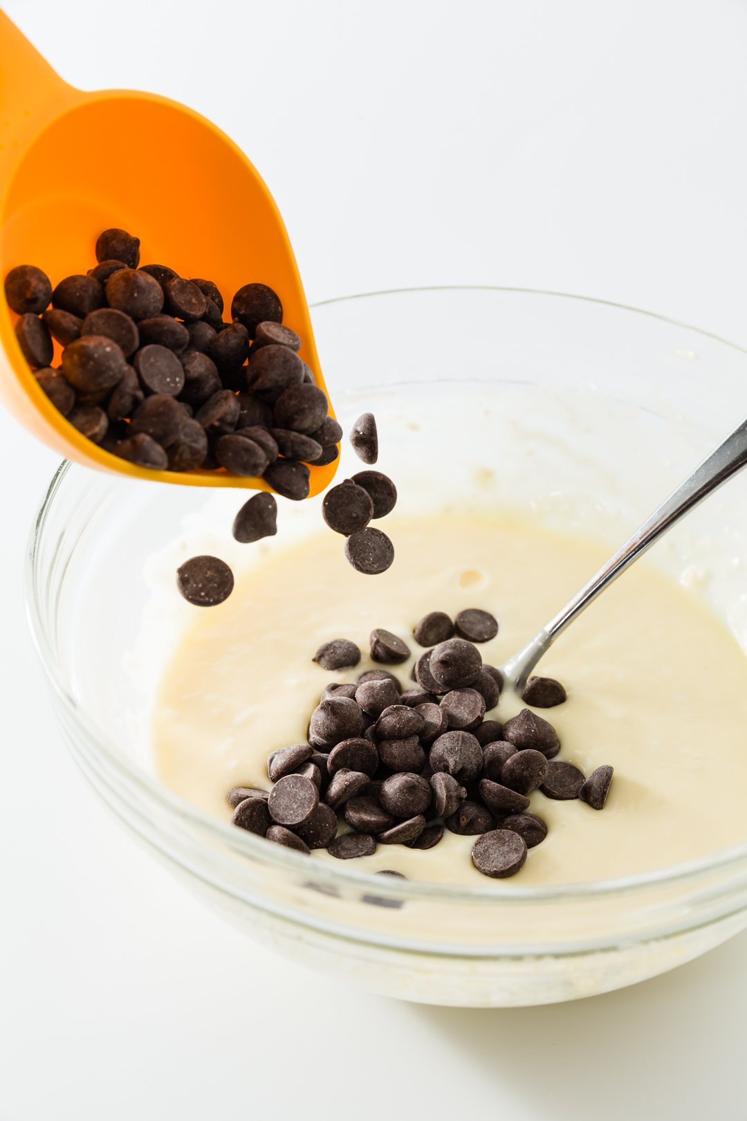 Chocolate chips being added to cheesecake topping