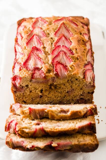 Una carga de pan de fresa y plátano con tres rebanadas cayendo