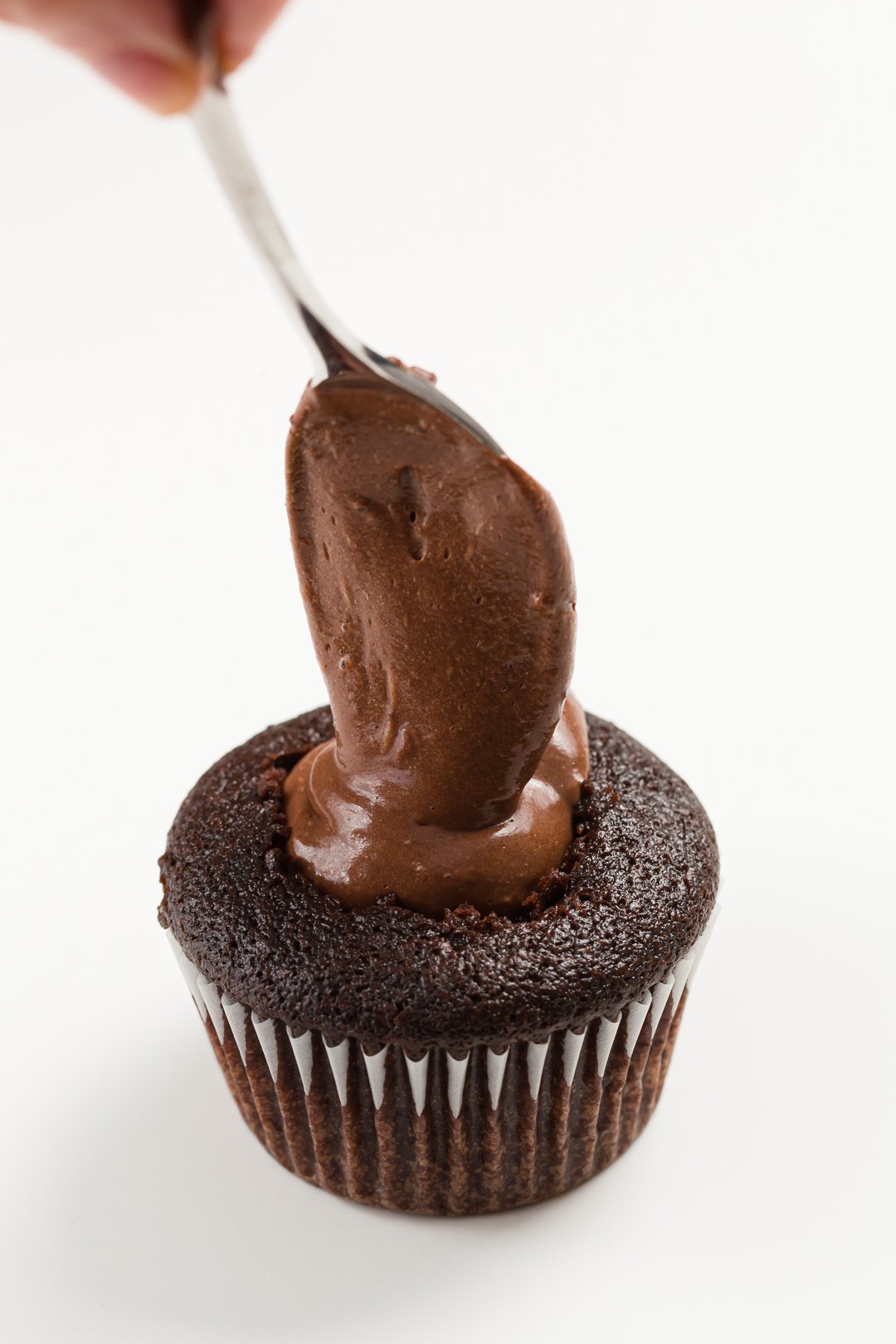 filling a cupcake with ganache