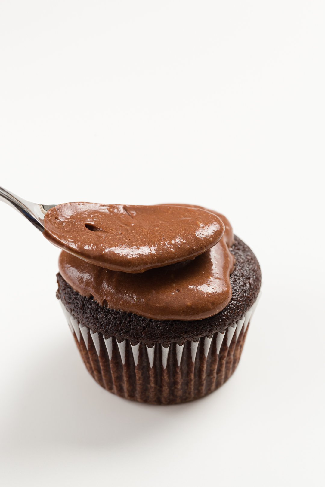 spreading ganache over the top of a filled cupcake