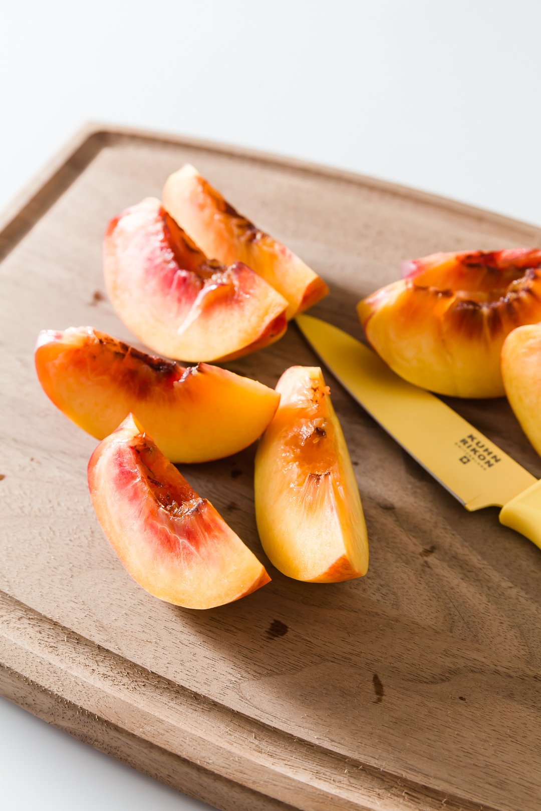 a cutting board with sliced peaches and a knife