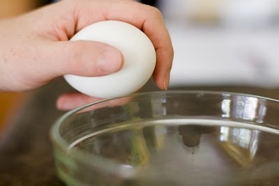 Cracking an egg against the edge of a bowl