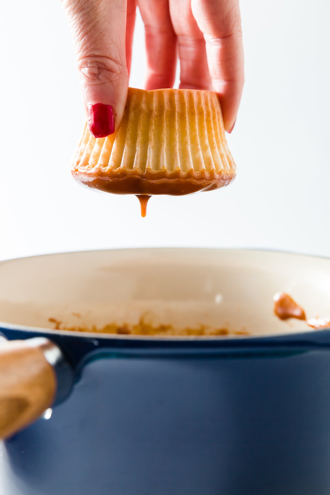 Dipping top of a cupcake in caramel icing