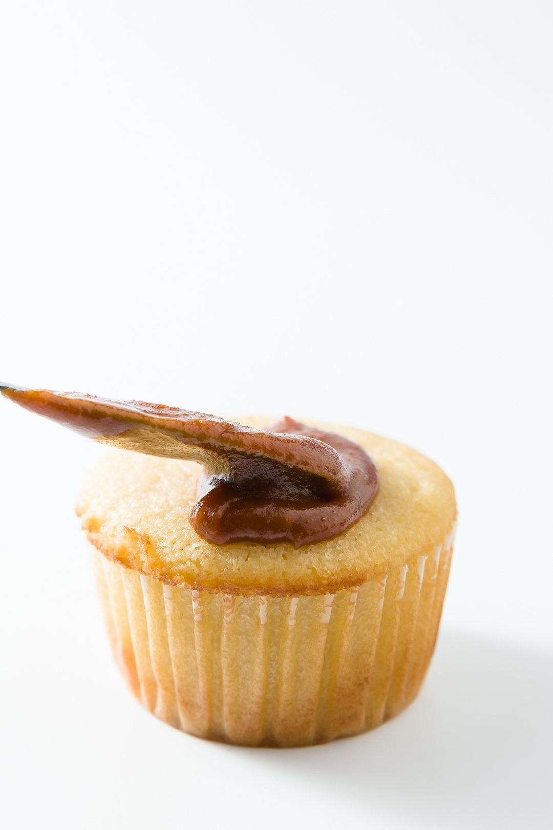 Caramel icing being spread onto a cupcake