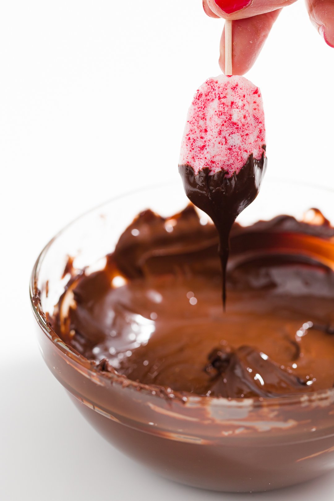 Dipping candy cane madeleine in chocolate