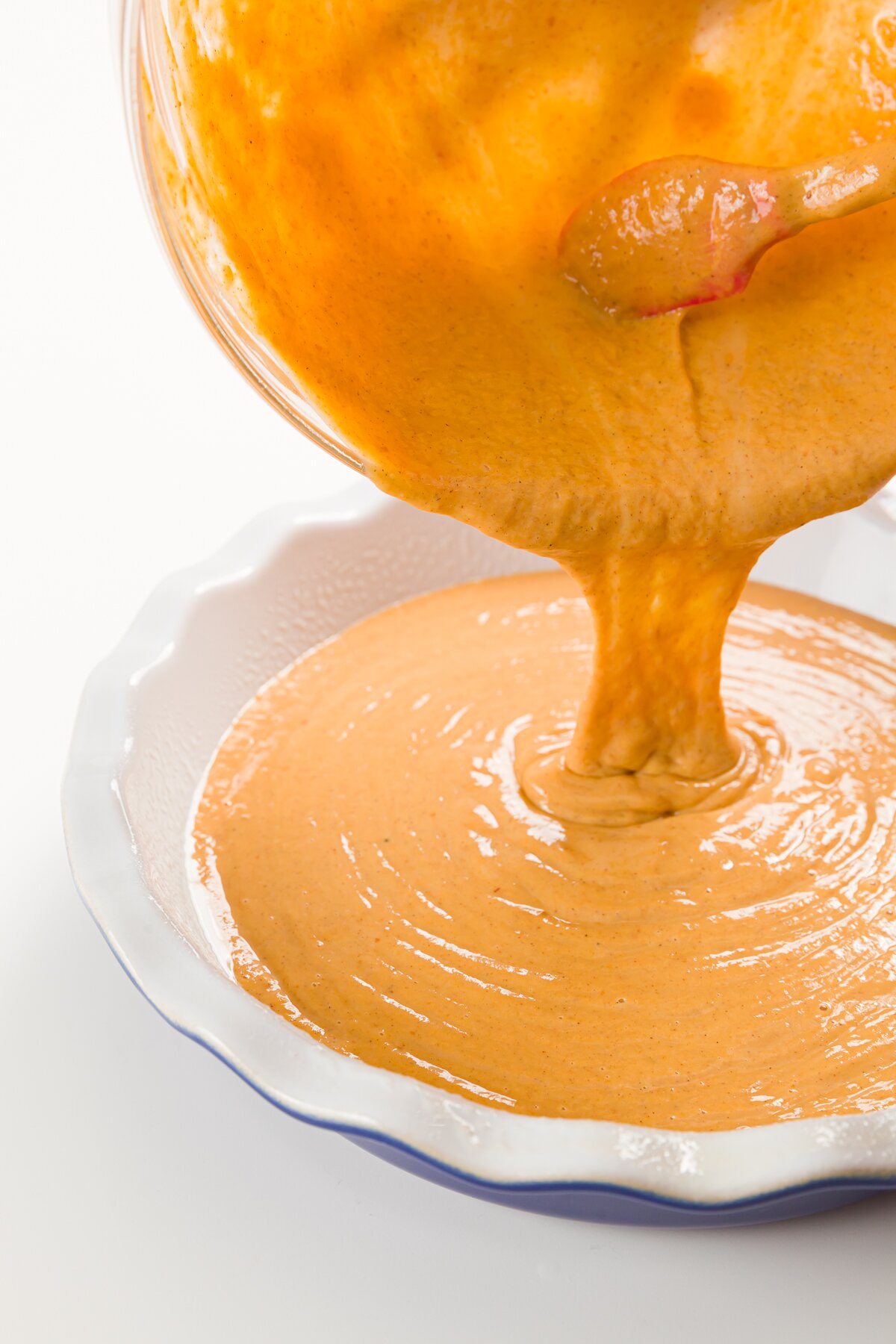 Pouring pumpkin pie filling into a pie pan