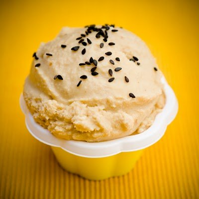 a yellow cup of miso ice cream topped with black sesame seeds