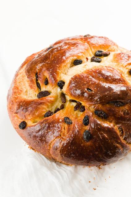 Round challah loaf with raisins on a white countertop