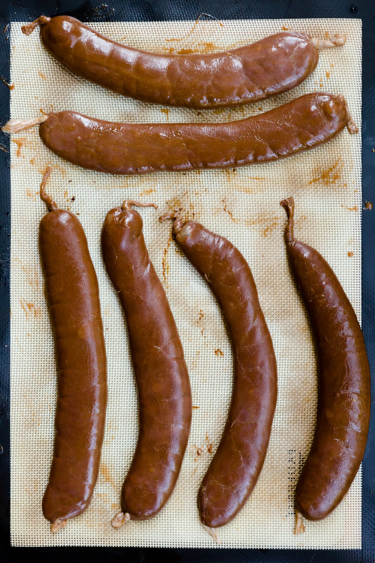 overhead view of six dessert sausages on a silicone mat prior to baking