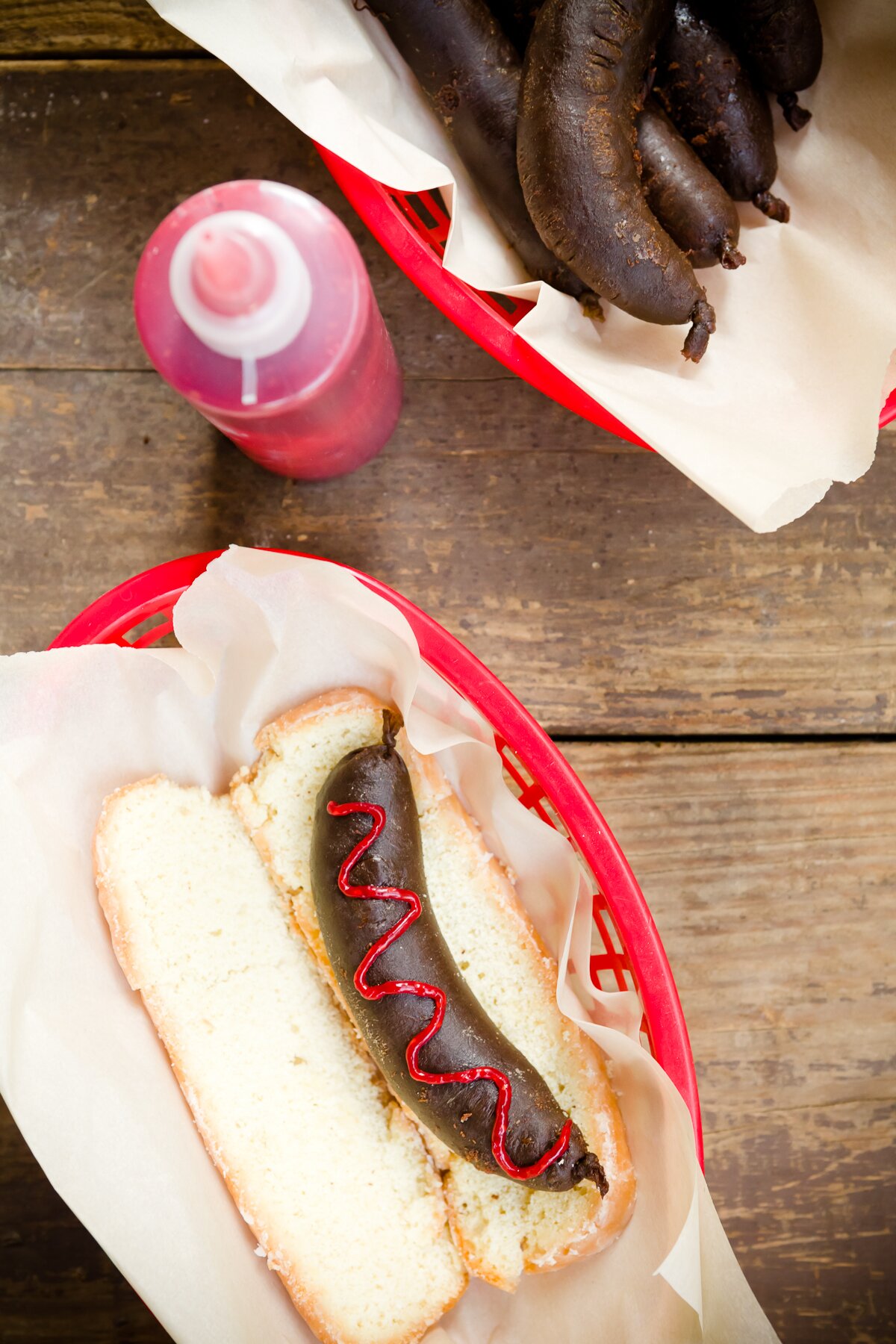 overhead view of dessert sausage with raspberry "ketchup" resting in a Long John donut