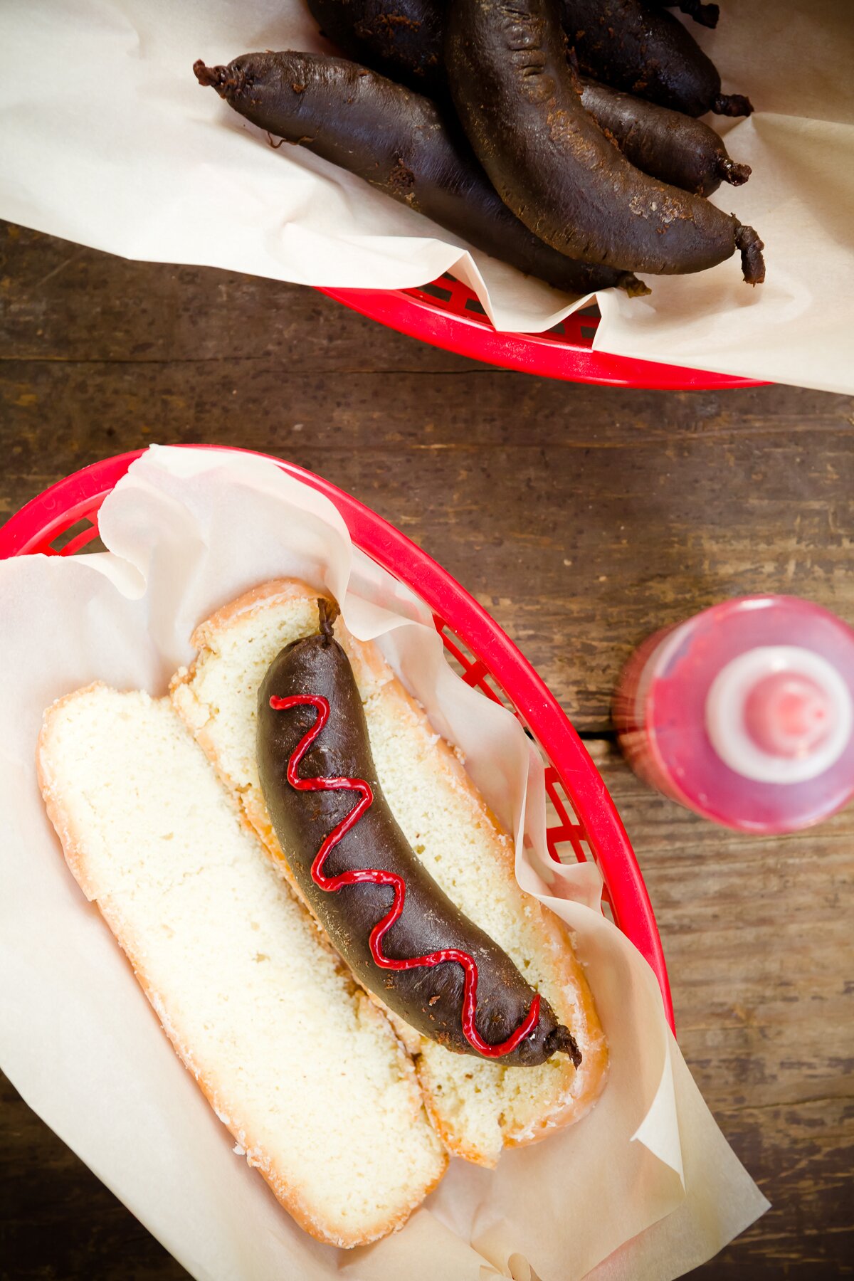 overhead view of dessert sausage with raspberry "ketchup" resting in a Long John donut