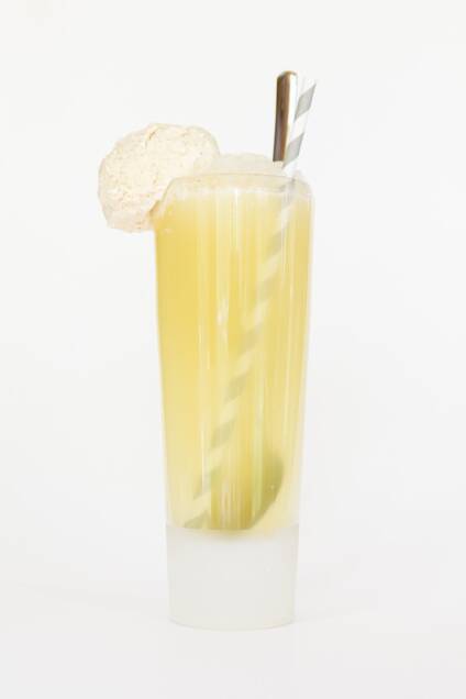 head-on view of a limoncello float in a tall glass with ice cream on the rim, served with a spoon and paper straw