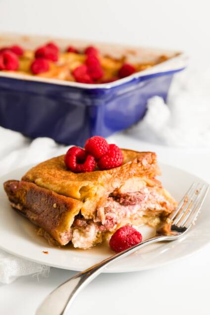Slice of raspberry stuffed French toast with the casserole dish in the background