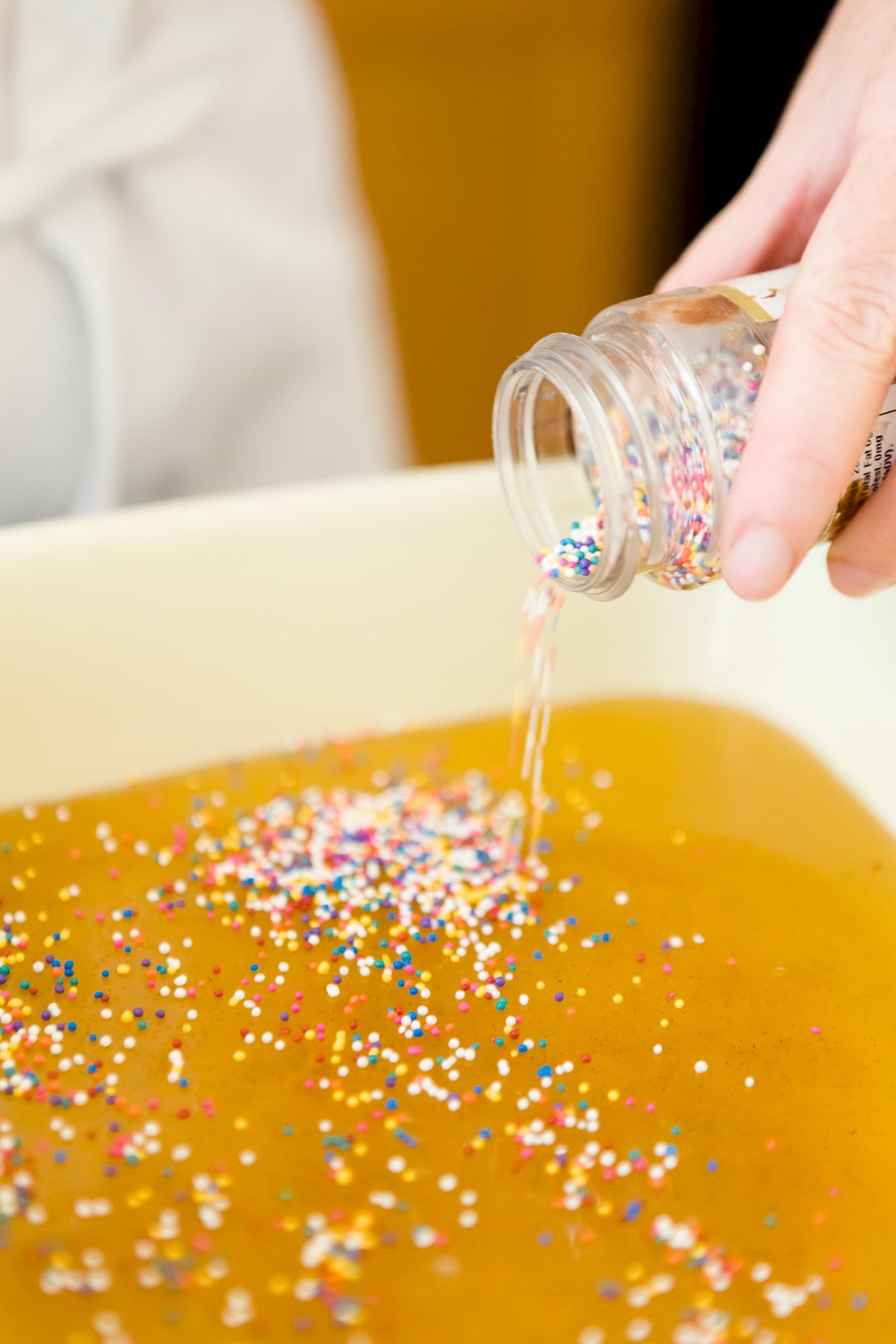 Adding nonpareils to taffy in a baking dish