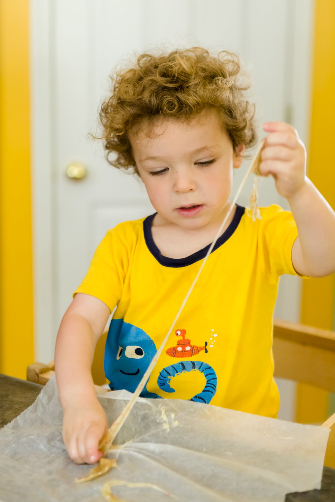 Toddler pulling a piece of salt water taffy over waxed paper