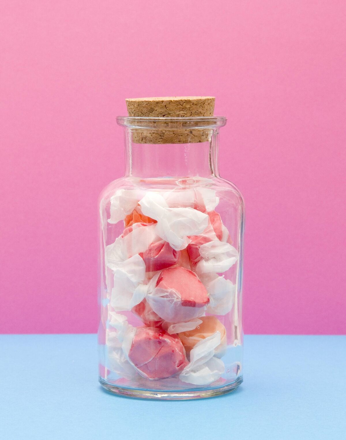 saltwater taffy in a jar with a pink background