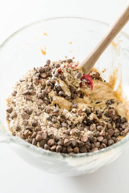 Revuelva la avena y las chispas de chocolate en la masa de muffins de plátano