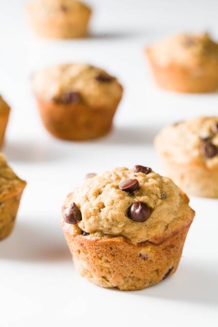 Banana oatmeal chocolate chip muffins scattered on a white background
