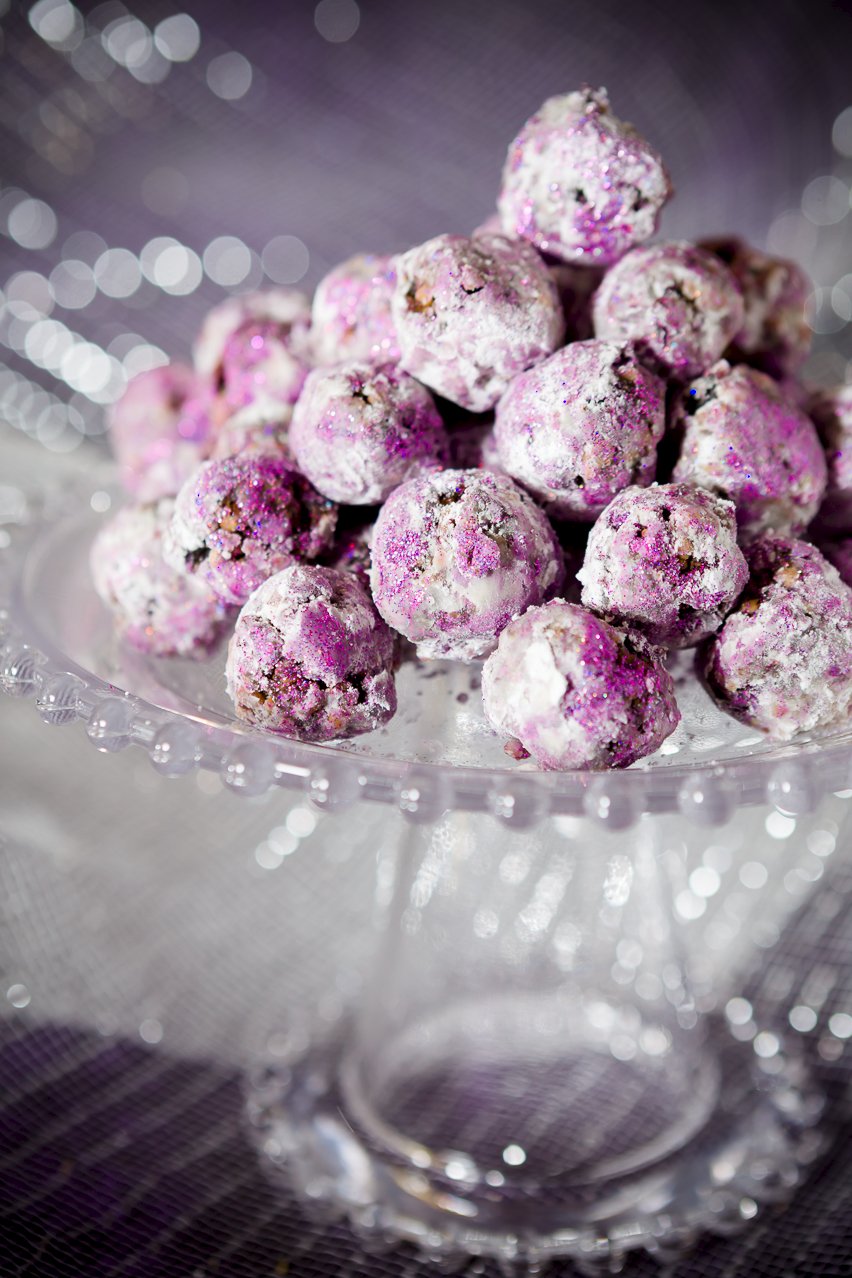 a number of sugar plums coated with edible glitter resting on a clear stand...