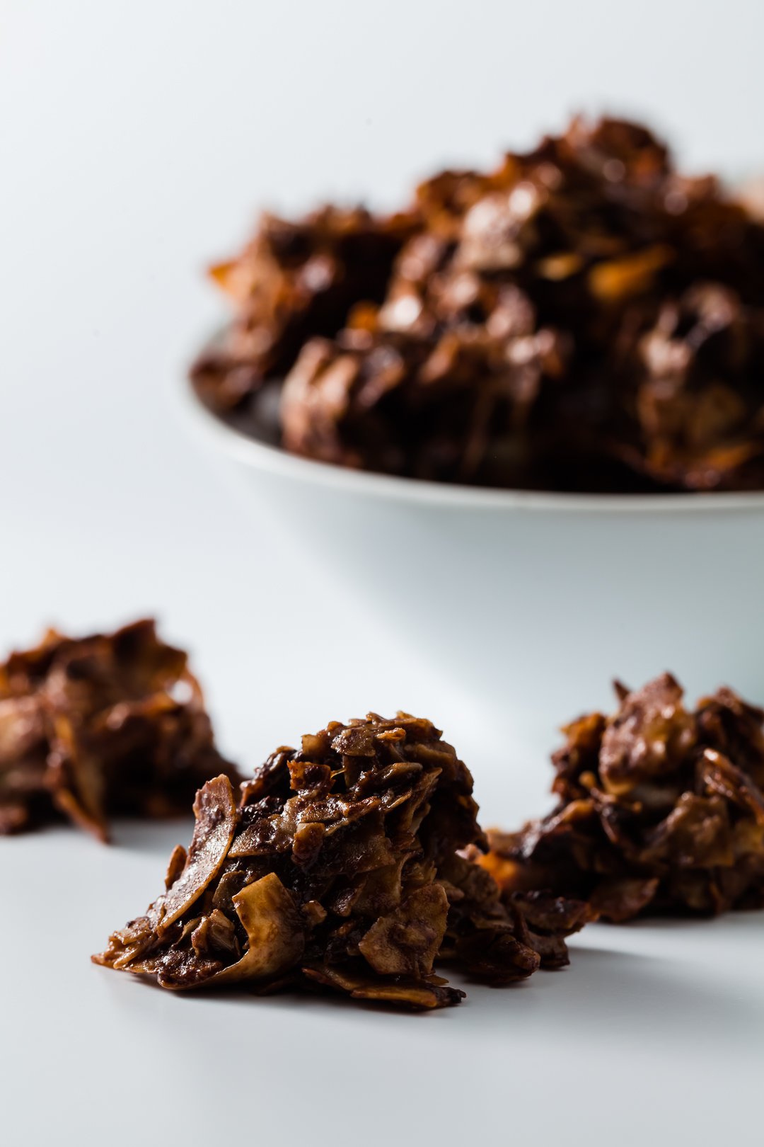 A bowl of chocolate macaroons with some in the front