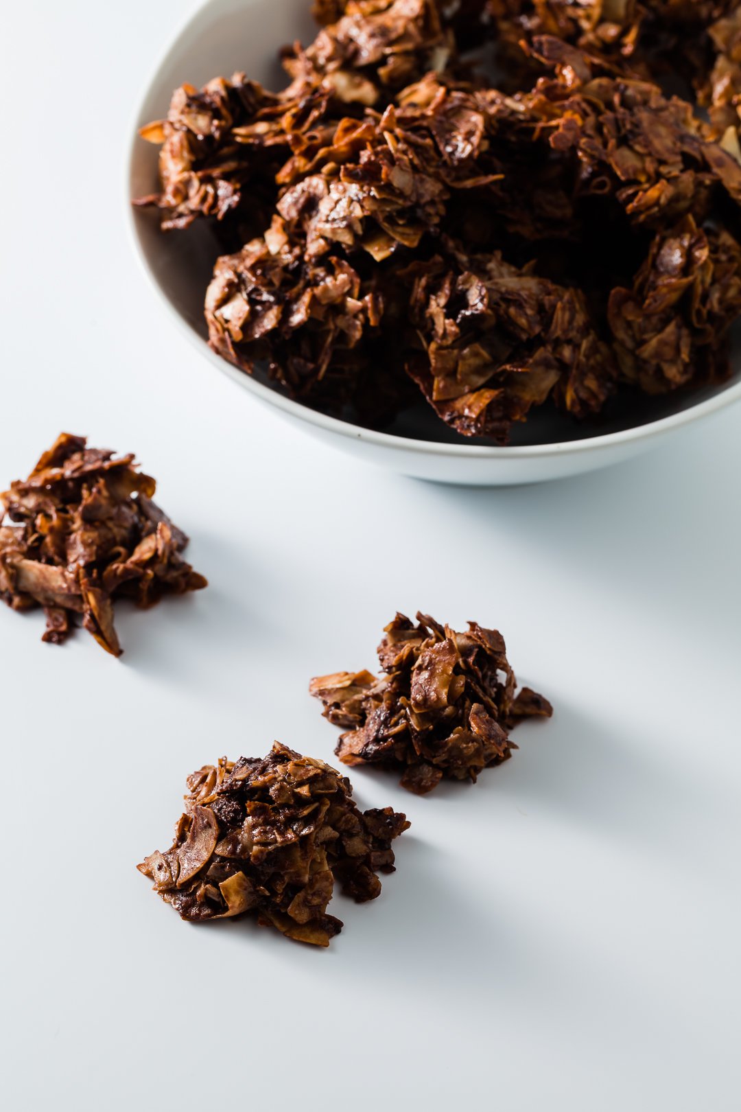 A bowl of chocolate macaroons with a few off to the side