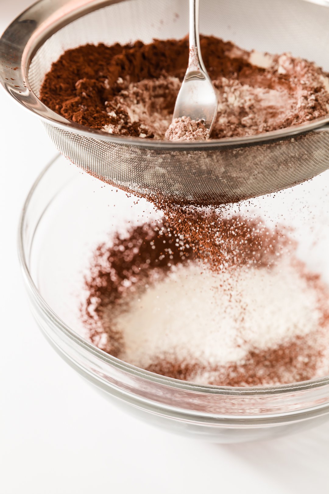 Sieve with dry ingredients including cocoa powder being sifted