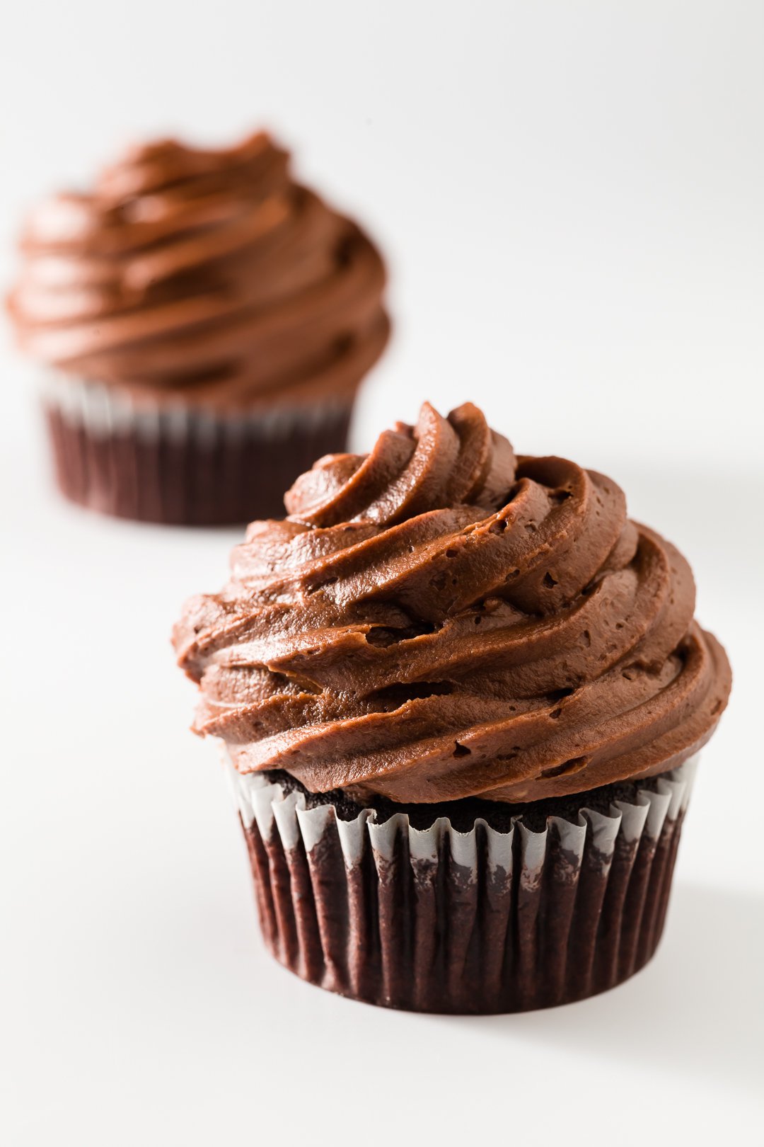 Two chocolate cupcakes on a white background