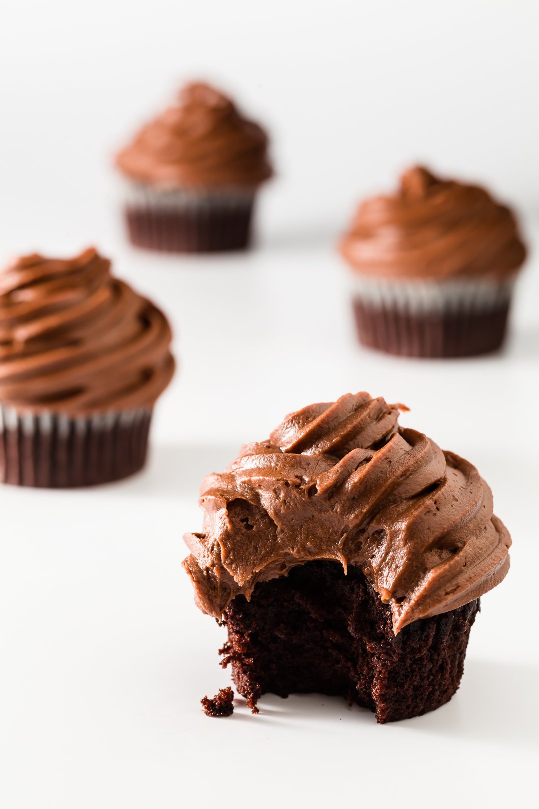 a chocolate cupcake with chocolate frosting on a white background.