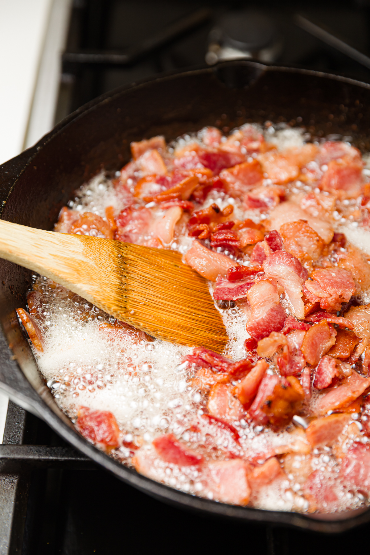 Bacon frying in a pan with lots of bacon grease.
