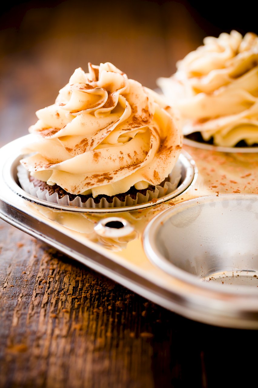 Tiramisu frosting on top of a chocolate cupcake in a cupcake tin