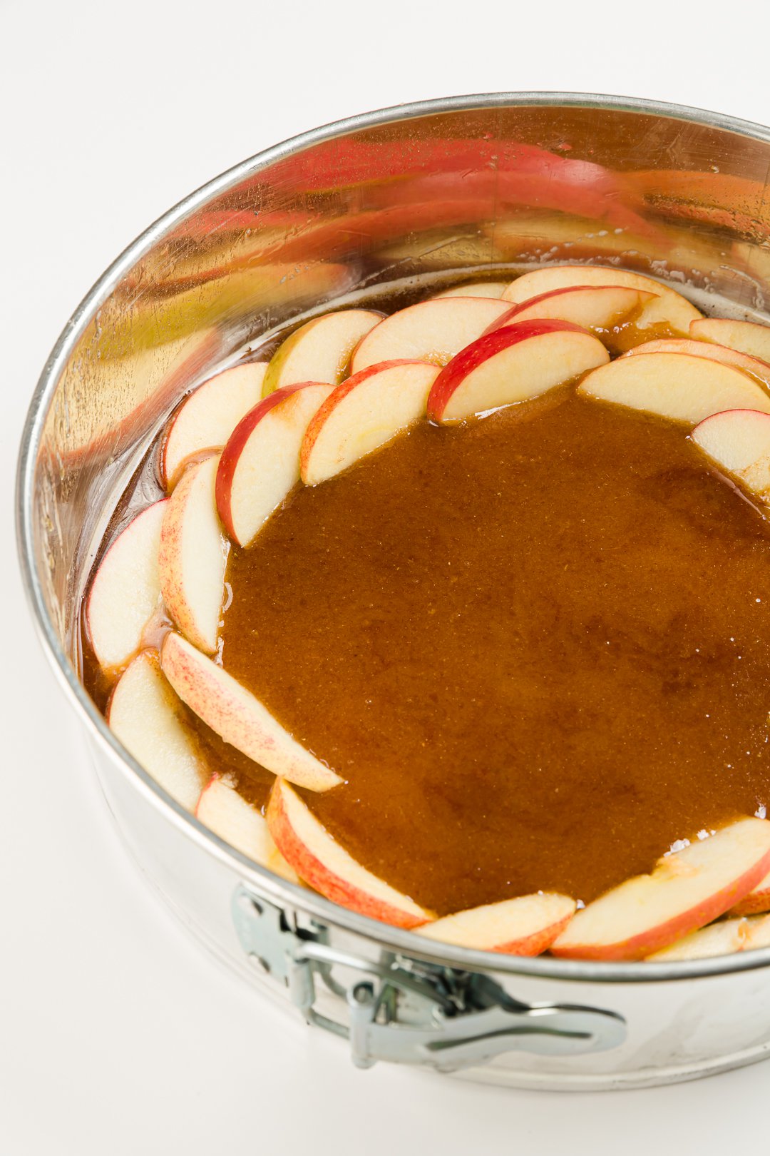 Apples arranged in a springform pan on top of caramel