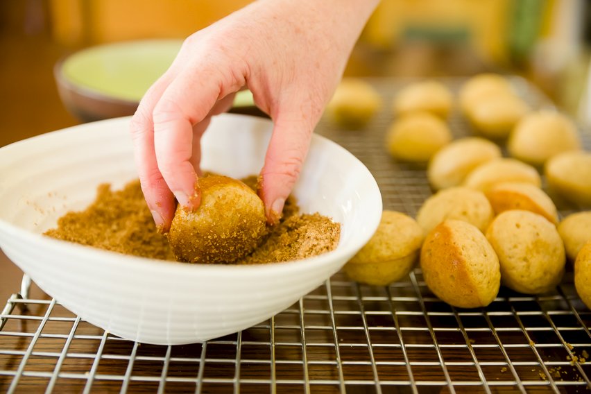 Dipping baked donuts into spices