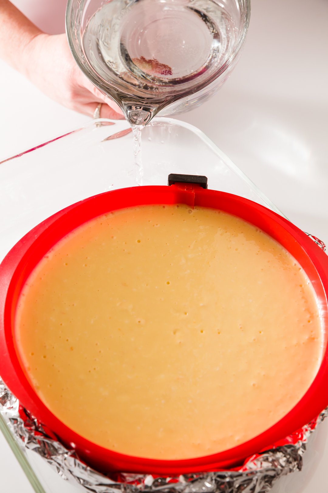 Orange cheesecake in baking dish with hot water being added