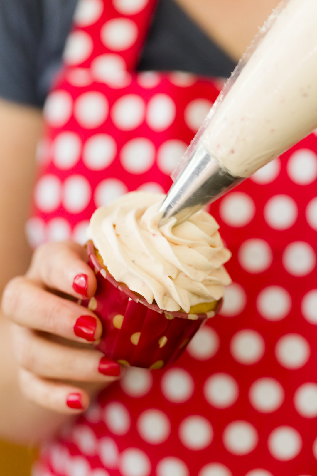 Strawberry Whipped Cream Frosting being piped onto a cupcake