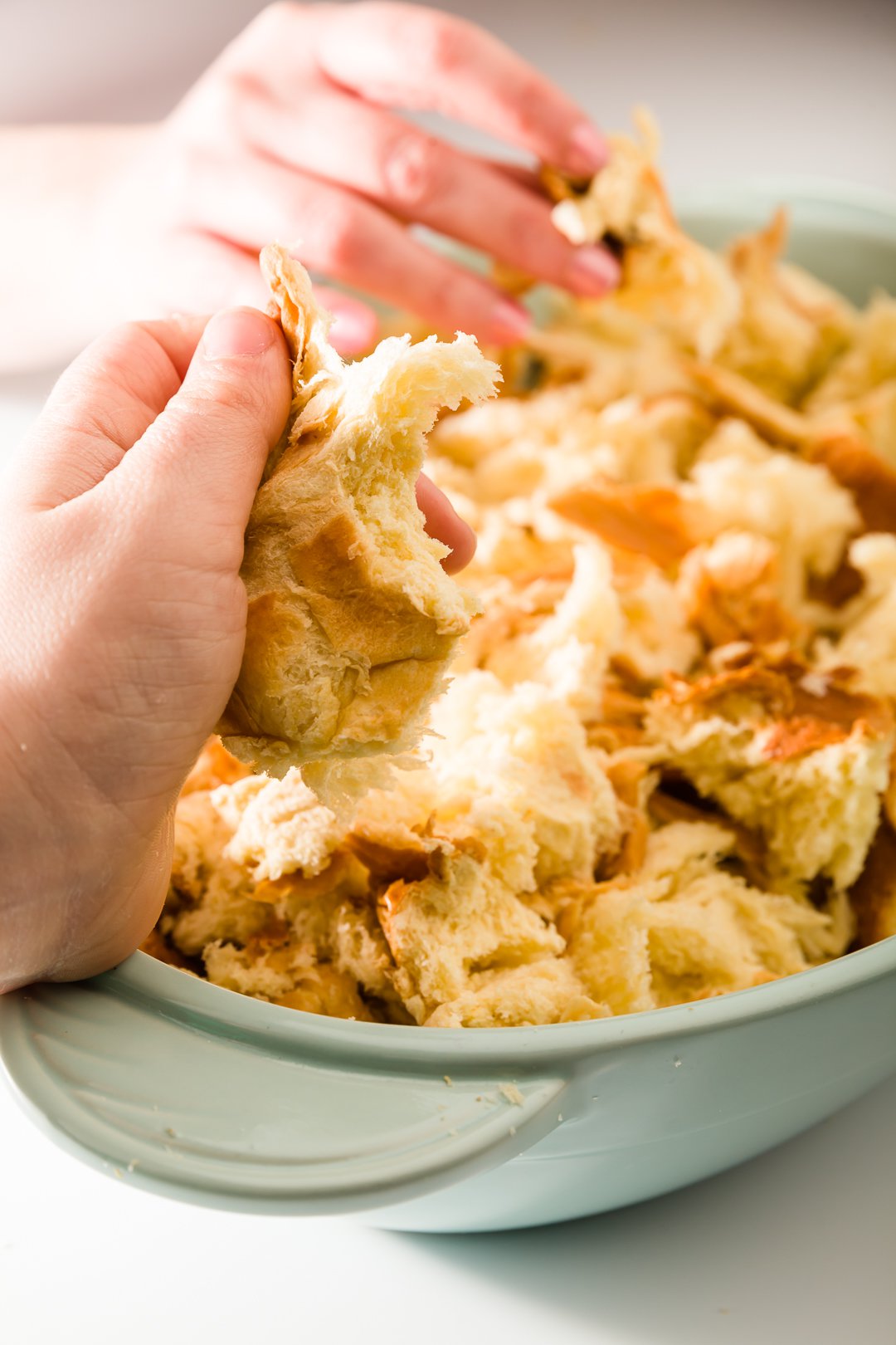 Brioche being ripped into a casserole dish